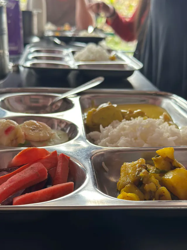 A steel thali with rice, curry and fruit