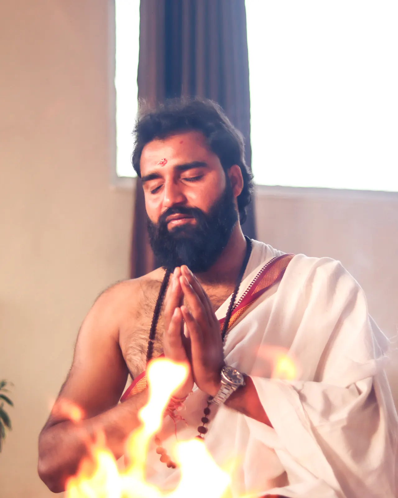 Yogi Arya with hands in prayer in front of the sacred fire