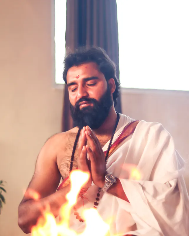 Yogi Arya with hands in prayer in front of the sacred fire