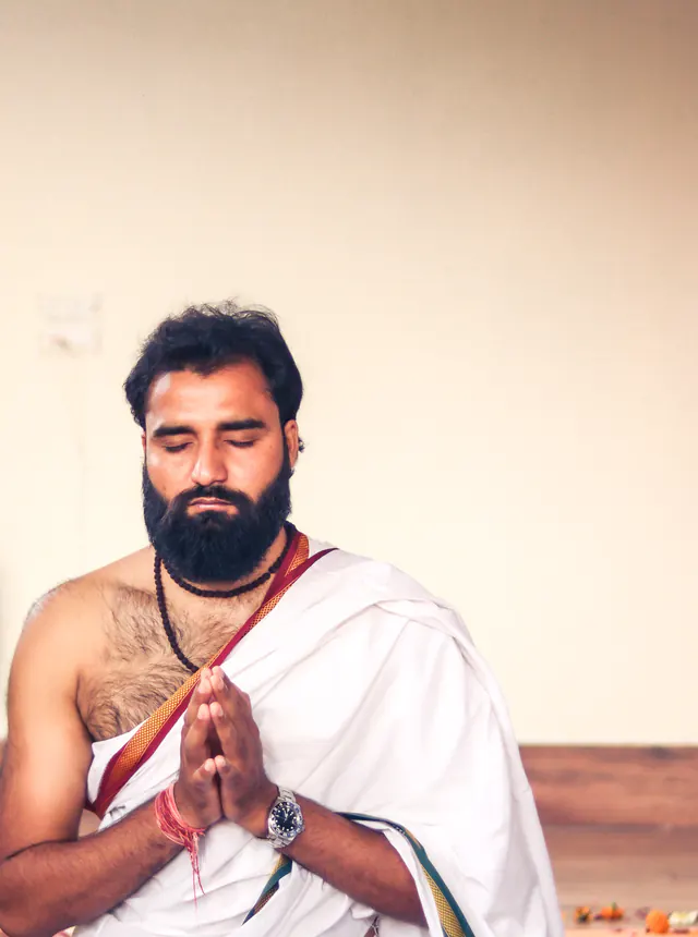 Yogi Arya sitting calmly with eyes closed and hands in prayer