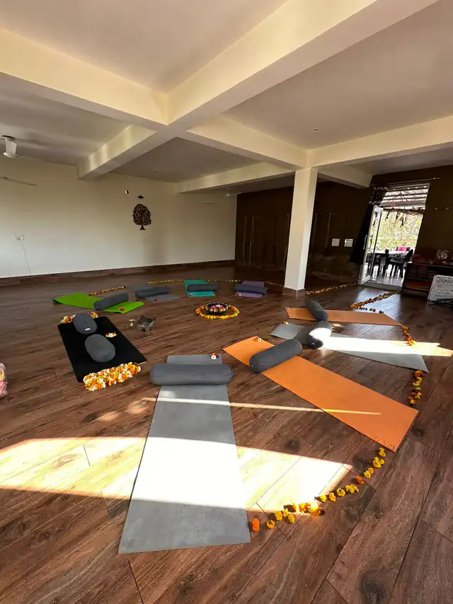 An empty yoga hall in daylight with mats, bolsters and rings of marigold petals